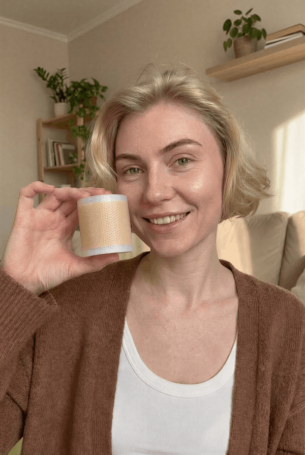Kvinna håller upp en rulle medicinsk silikontejp för hudvård.