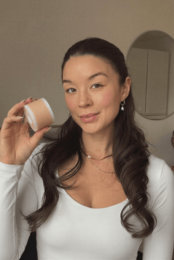 Kvinna håller upp en rulle medicinsk silikontejp för hudvård.