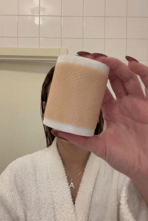 Rulle medicinsk silikontejp för hudvård hålls upp framför ansiktet.